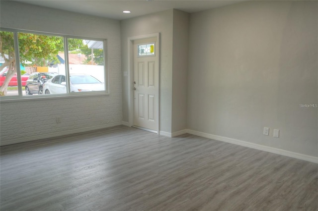 empty room featuring hardwood / wood-style floors and brick wall