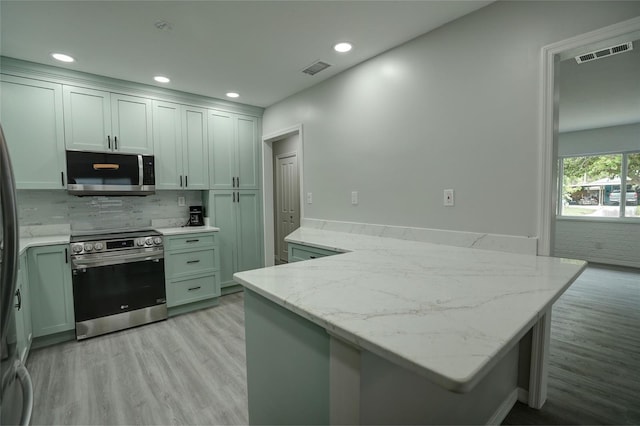 kitchen with light stone countertops, stainless steel appliances, tasteful backsplash, light hardwood / wood-style flooring, and kitchen peninsula