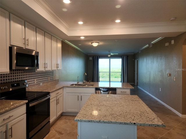 kitchen with appliances with stainless steel finishes, ornamental molding, sink, white cabinets, and a kitchen island