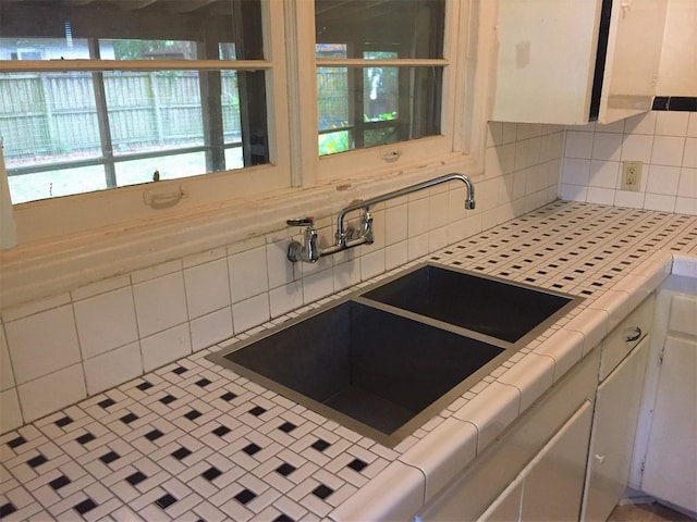 kitchen with sink, tile countertops, tasteful backsplash, and white cabinetry