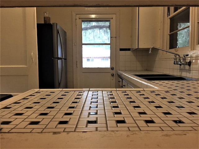 kitchen with sink, decorative backsplash, and stainless steel refrigerator