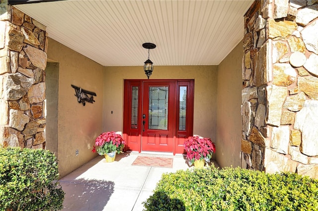 doorway to property featuring stone siding and stucco siding