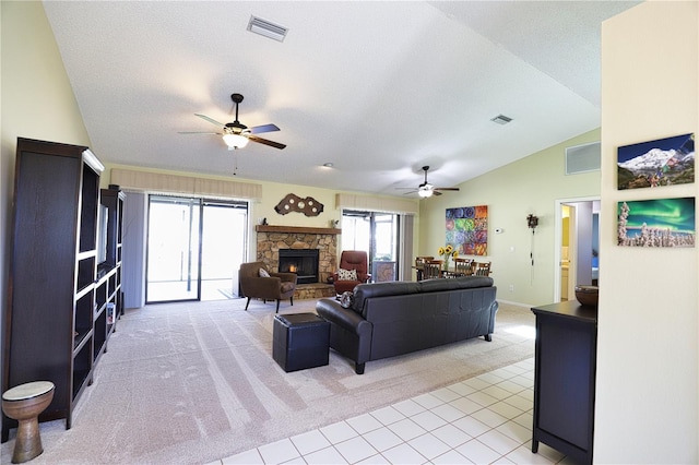 living room featuring vaulted ceiling, a stone fireplace, and visible vents