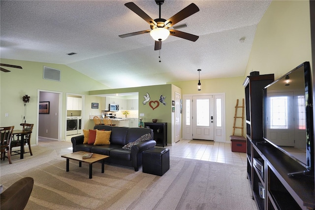 living area with lofted ceiling, light colored carpet, visible vents, washer / clothes dryer, and plenty of natural light