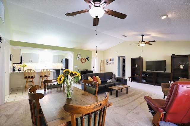 dining room with light tile patterned floors, a ceiling fan, light colored carpet, lofted ceiling, and a textured ceiling