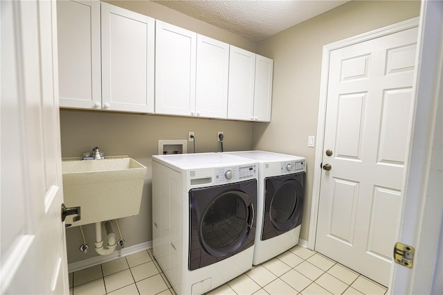 washroom with light tile patterned floors, cabinet space, a textured ceiling, separate washer and dryer, and baseboards