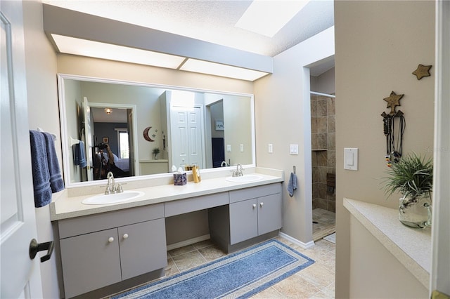 bathroom with a tile shower, double vanity, tile patterned flooring, and a sink