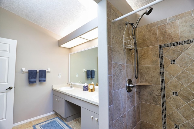 bathroom featuring double vanity, a textured ceiling, a sink, and tiled shower