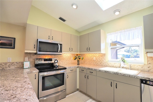 kitchen with visible vents, vaulted ceiling, stainless steel appliances, light countertops, and a sink