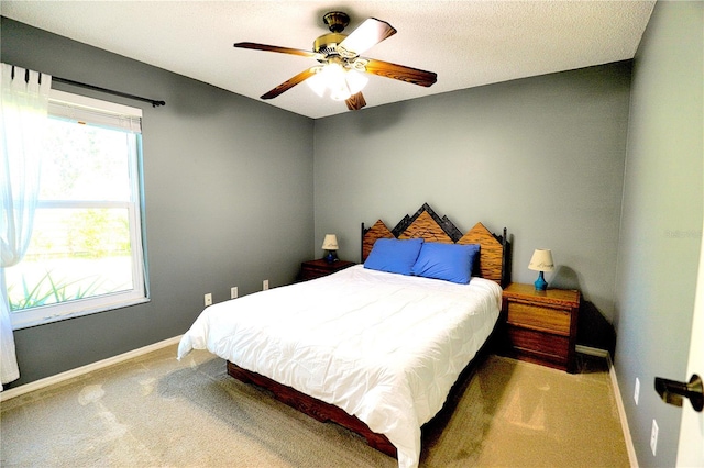 carpeted bedroom with ceiling fan, a textured ceiling, and baseboards