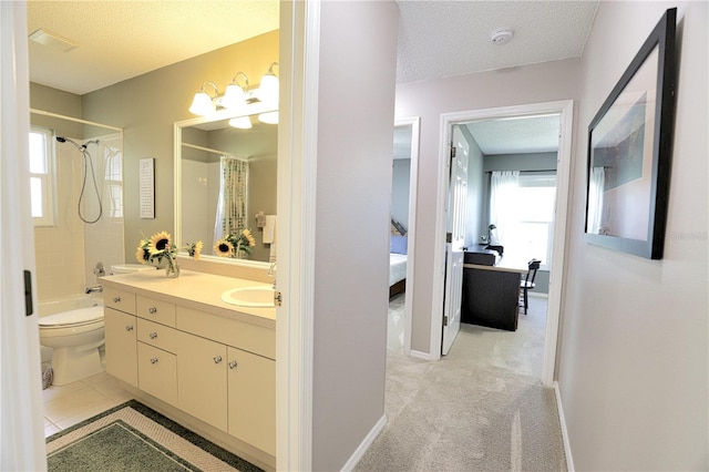 full bathroom with double vanity, ensuite bathroom, a sink, a textured ceiling, and baseboards