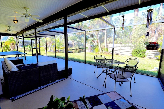 sunroom / solarium featuring a water view and a ceiling fan