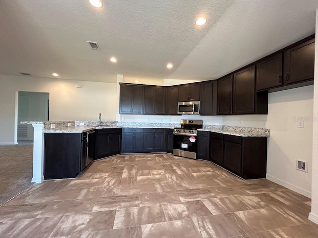 kitchen featuring light stone countertops, kitchen peninsula, dark brown cabinetry, and stainless steel appliances