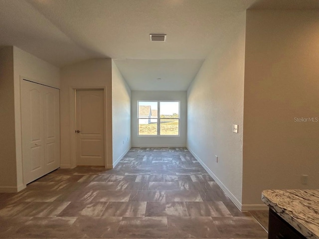 hall with a textured ceiling and lofted ceiling