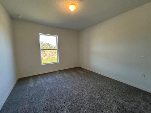 spare room featuring dark colored carpet