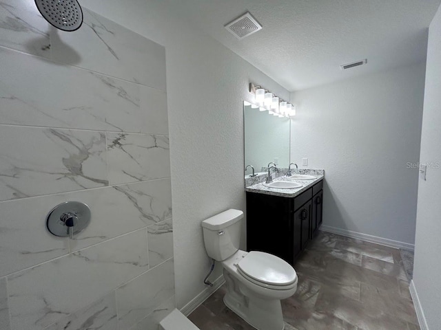 bathroom featuring toilet, vanity, a shower, and a textured ceiling