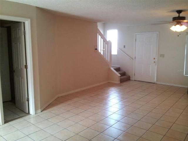 interior space with ceiling fan, light tile patterned floors, and a textured ceiling