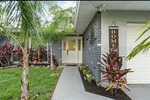 view of exterior entry with a garage and a lawn