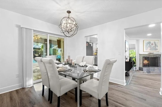 dining area with a fireplace, hardwood / wood-style floors, and an inviting chandelier