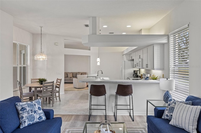 kitchen featuring white cabinets, a breakfast bar, decorative light fixtures, and kitchen peninsula