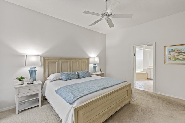 bedroom featuring ceiling fan, light colored carpet, and ensuite bath