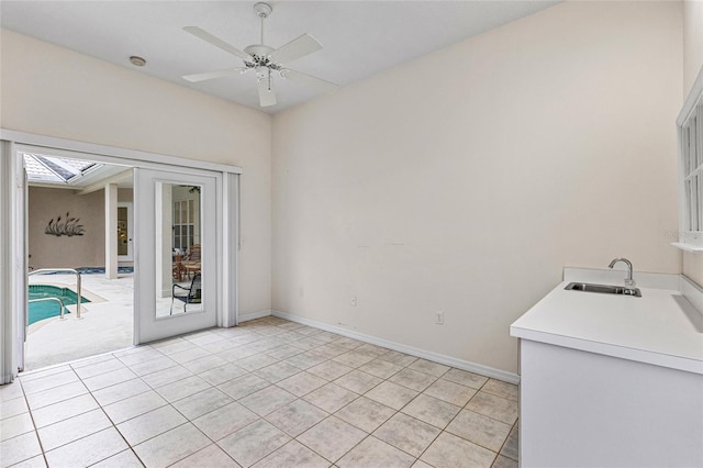 tiled empty room with french doors, ceiling fan, and sink