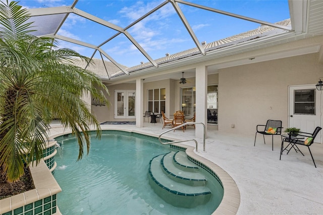 view of swimming pool featuring pool water feature, ceiling fan, a lanai, french doors, and a patio area