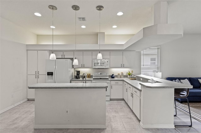 kitchen with white appliances, hanging light fixtures, a kitchen bar, a high ceiling, and white cabinetry