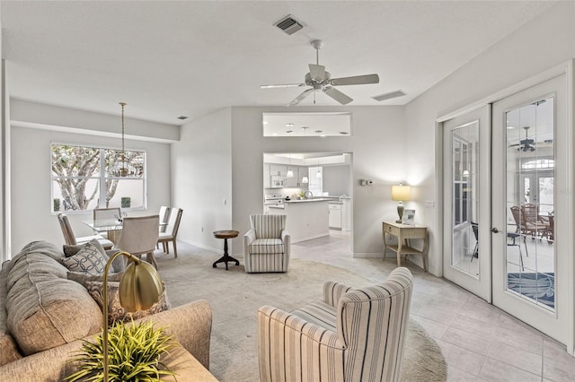 tiled living room featuring ceiling fan and french doors