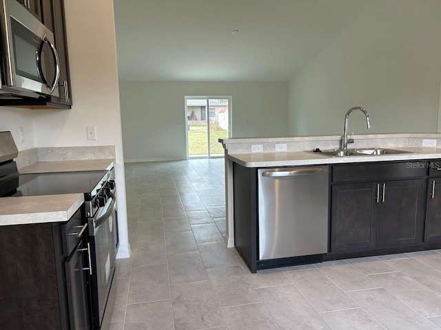 kitchen with light tile patterned flooring, stainless steel appliances, a sink, open floor plan, and light countertops