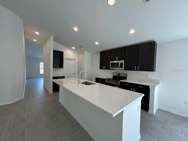 kitchen featuring a center island with sink, lofted ceiling, stainless steel appliances, light countertops, and a sink