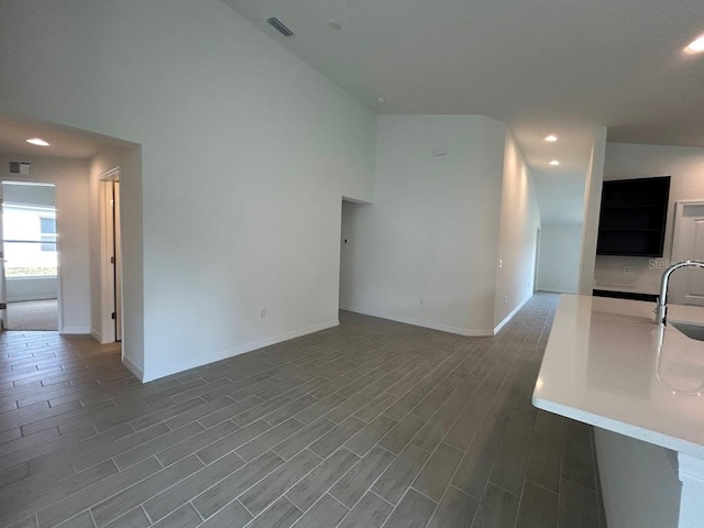 unfurnished living room featuring dark wood-type flooring, recessed lighting, a sink, and baseboards