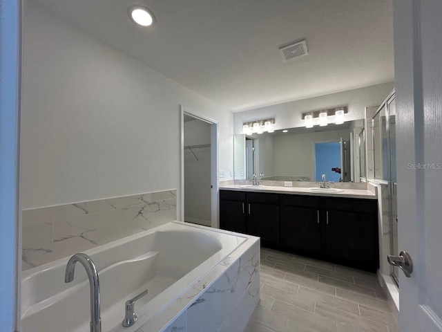 bathroom featuring a bath, double vanity, a sink, and visible vents