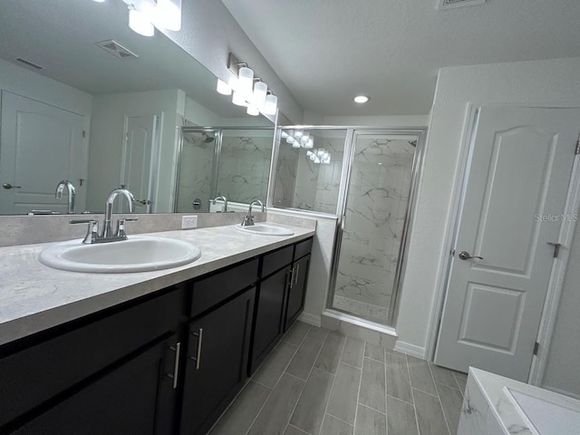 full bathroom with a marble finish shower, double vanity, a sink, and visible vents