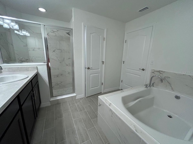 full bathroom featuring visible vents, a garden tub, vanity, and a marble finish shower