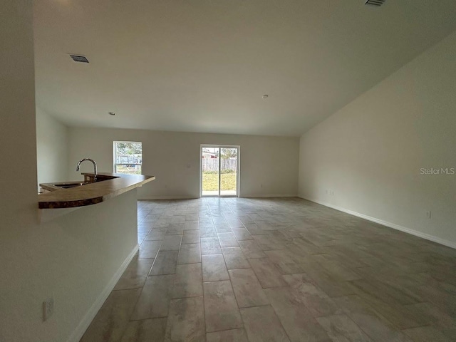 unfurnished living room featuring baseboards, visible vents, and a sink