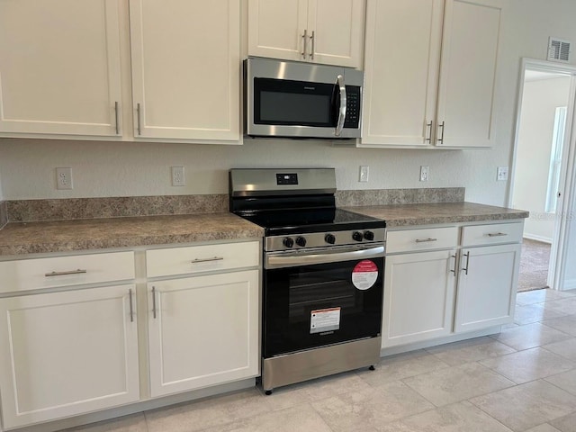 kitchen with dark countertops, white cabinetry, visible vents, and stainless steel appliances