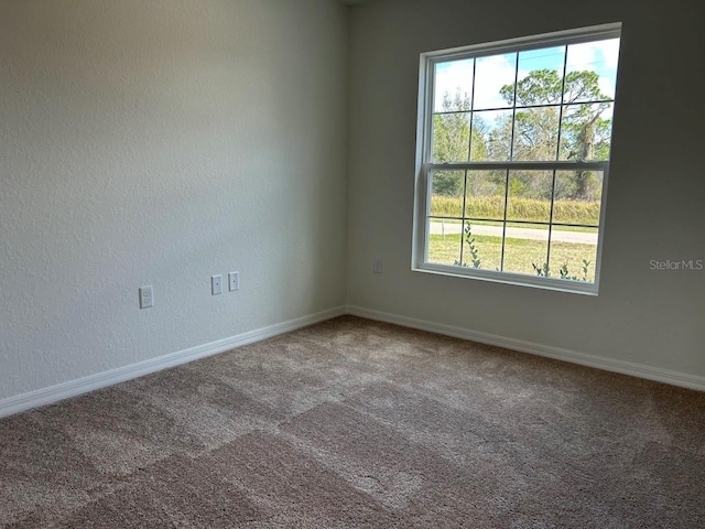 carpeted empty room with a textured wall and baseboards