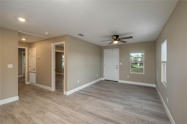 spare room with a textured ceiling, light wood-type flooring, and ceiling fan