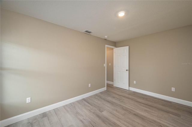 unfurnished room featuring a textured ceiling and light wood-type flooring