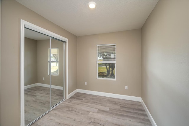 unfurnished bedroom featuring a closet, a textured ceiling, and light wood-type flooring