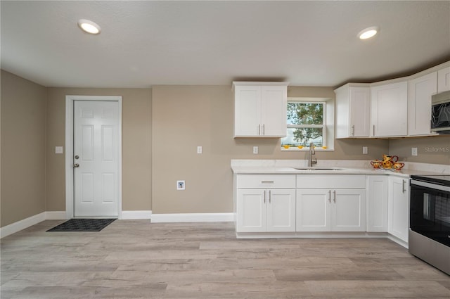 kitchen with white cabinets, light wood-type flooring, sink, and stainless steel appliances