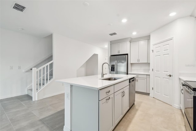 kitchen featuring gray cabinets, sink, a center island with sink, and stainless steel appliances