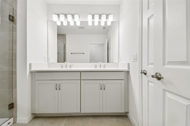 bathroom with a shower with shower door, vanity, and tile patterned flooring