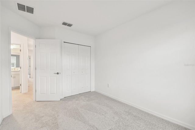 unfurnished bedroom with light carpet and a closet