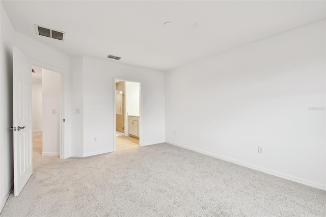 unfurnished bedroom with light colored carpet and connected bathroom