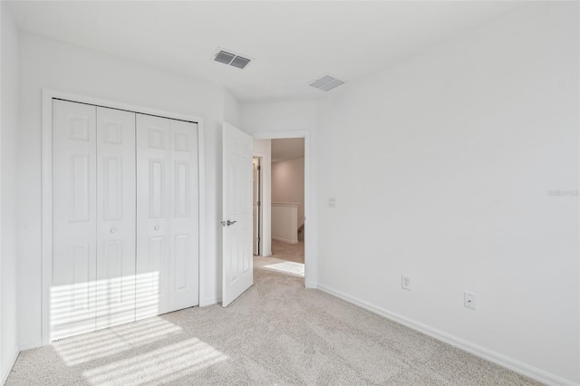 unfurnished bedroom featuring light colored carpet and a closet