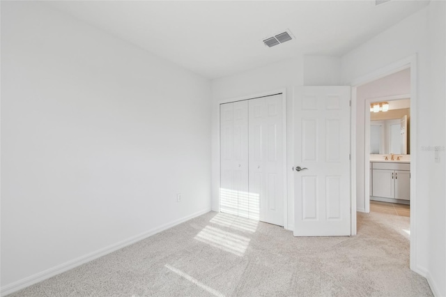 unfurnished bedroom featuring a closet, light colored carpet, and sink