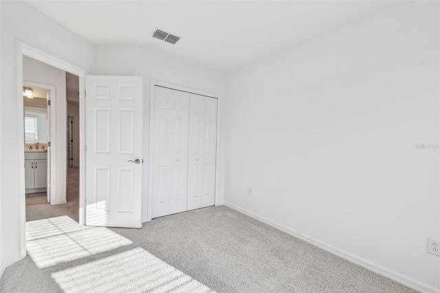 unfurnished bedroom featuring light carpet and a closet