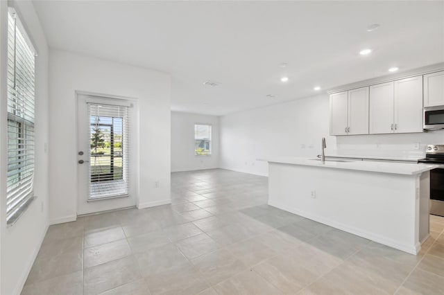 kitchen with sink, white cabinetry, appliances with stainless steel finishes, an island with sink, and light tile patterned floors